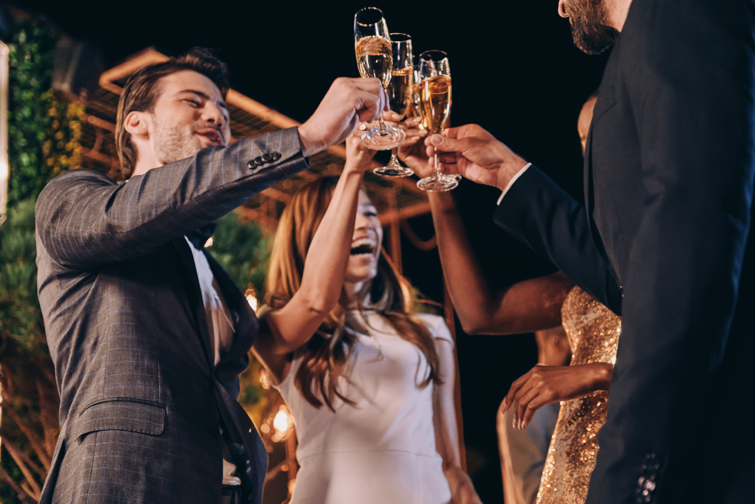 group of people in formalwear toasting with champagne and smilin